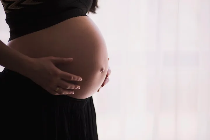 Mujer embarazada acunando su tripa con las manos