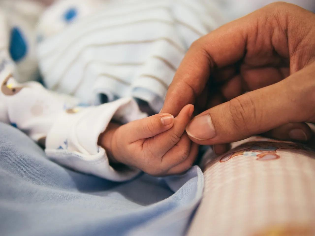 Mano de un bebé recién nacido sujetando un dedo adulto