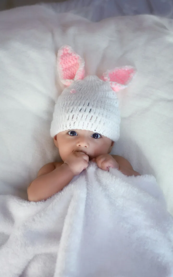 Bebé recién nacido con gorrito blanco, los primeros días tras el nacimiento